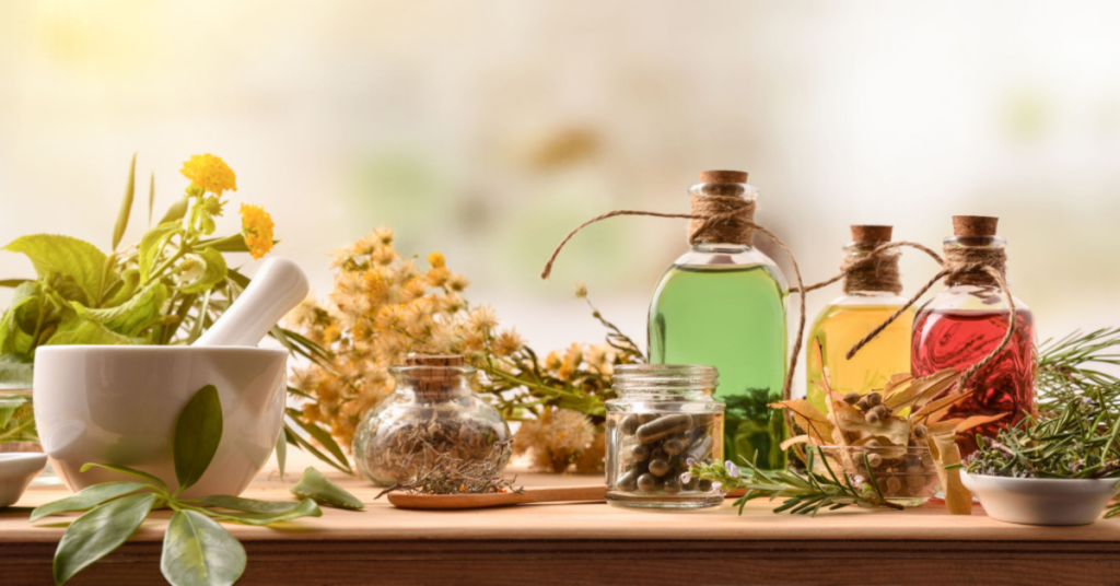 About Us - Image featuring a variety of herbs, an imam dasta (mortar and pestle), and glass bottles containing herbal extracts, illustrating the natural ingredients used in the Ayurvedic manufacturing process.